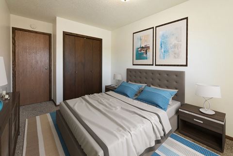 a bedroom with a bed and two doors. Fargo, ND Maplewood Bend Apartments