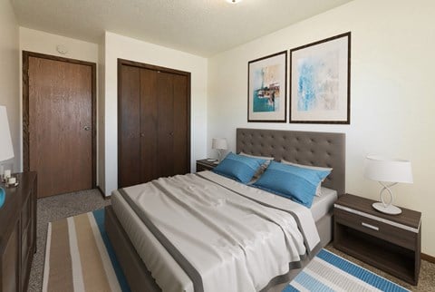 a bedroom with a bed and two doors. Fargo, ND Maplewood Bend Apartments