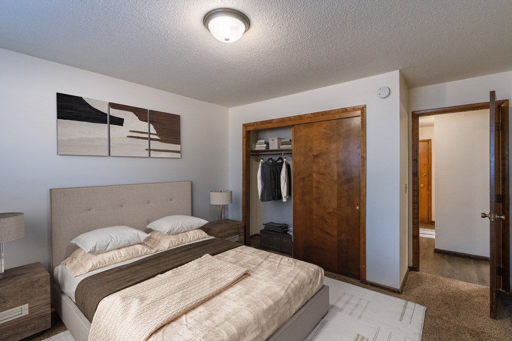 a bedroom with a bed and a closet with a closet door. Fargo, ND Martha Alice Apartments