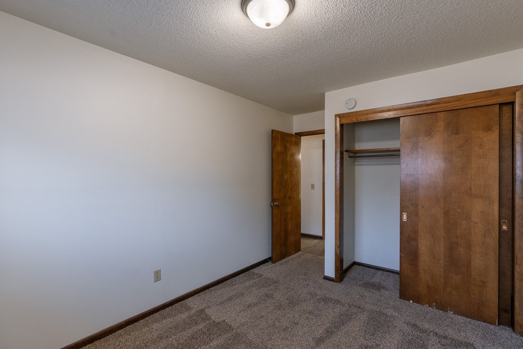 a bedroom with a closet and a door to a bathroom. Fargo, ND Martha Alice Apartments
