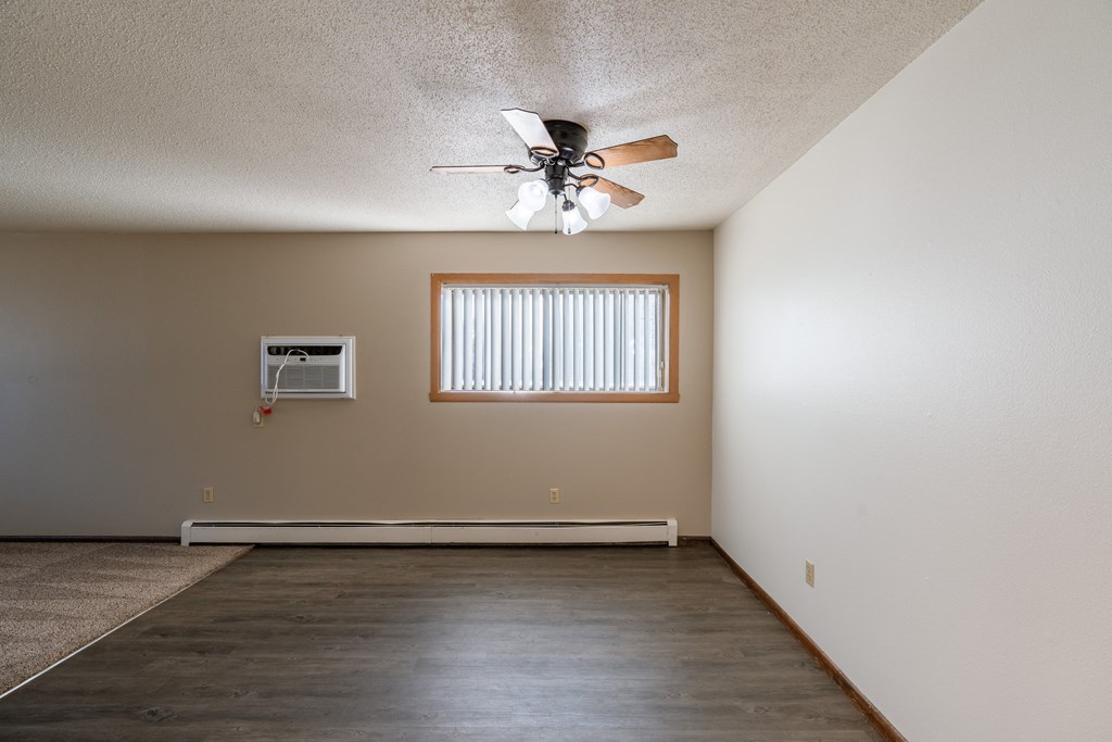 an empty living room with a ceiling fan and a window