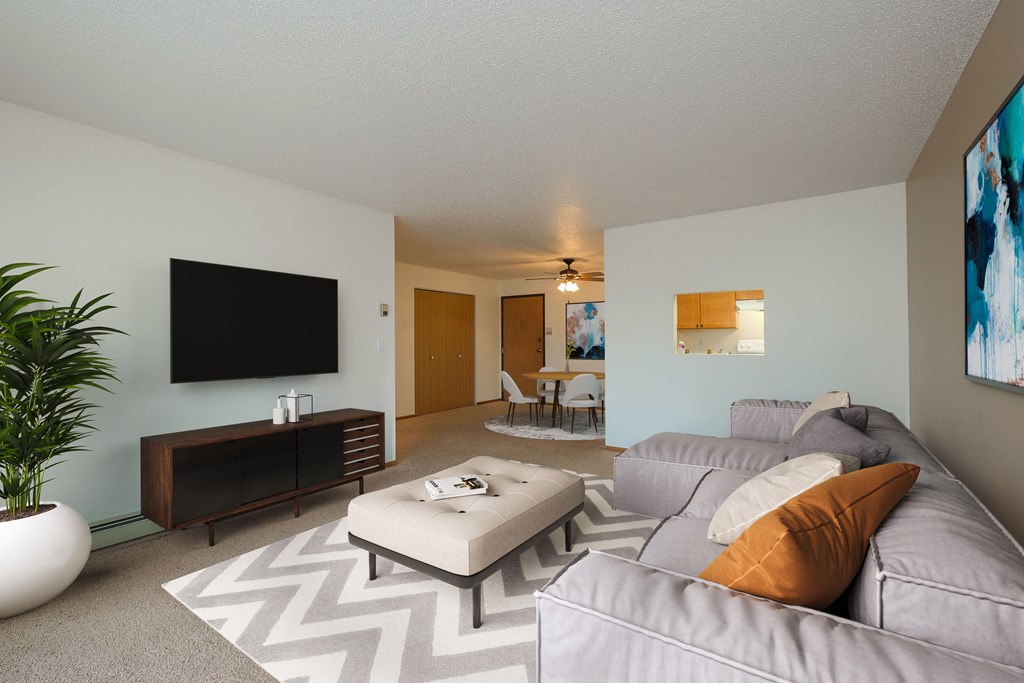 a living room with a large couch and a tv. Fargo, ND Maybrook Apartments