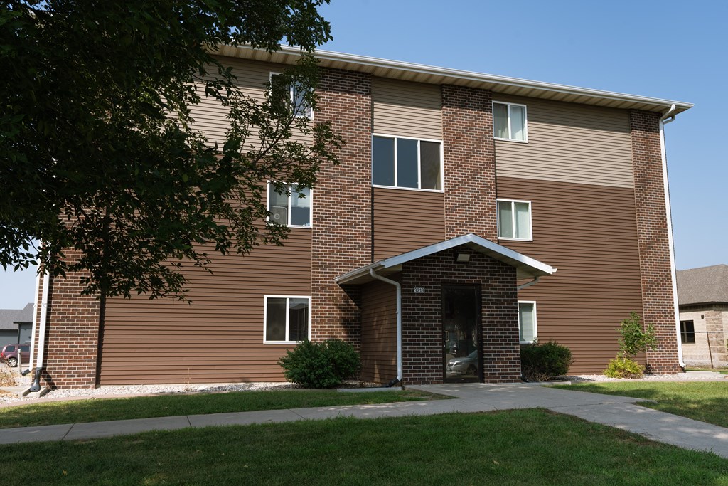 a brick apartment building with a sidewalk in front of it. Fargo, ND Maybrook Apartments