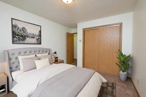 Fargo, ND Monticello. A bedroom with a large bed with white bedding and a closet for extra storage.