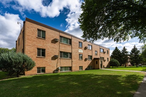 a brick apartment building with green grass and trees. Fargo, ND Morningside Apartments