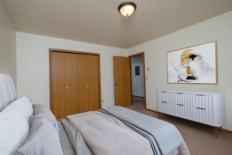 a bedroom with a bed and a closet and a door to a bathroom. Fargo, ND Oak Court Apartments