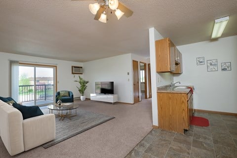 a living room with a couch and a table and a television. Fargo, ND Oak Court Apartments