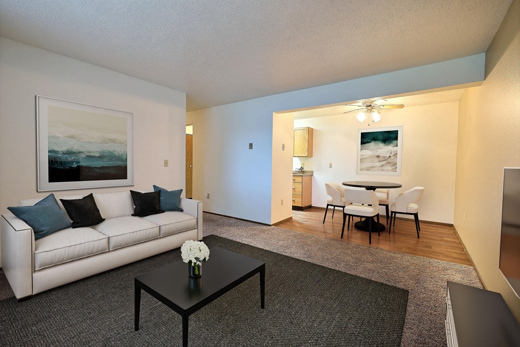 a living room with a couch and a coffee table and a dining room and kitchen. Fargo, ND Pacific Park 2 Apartments