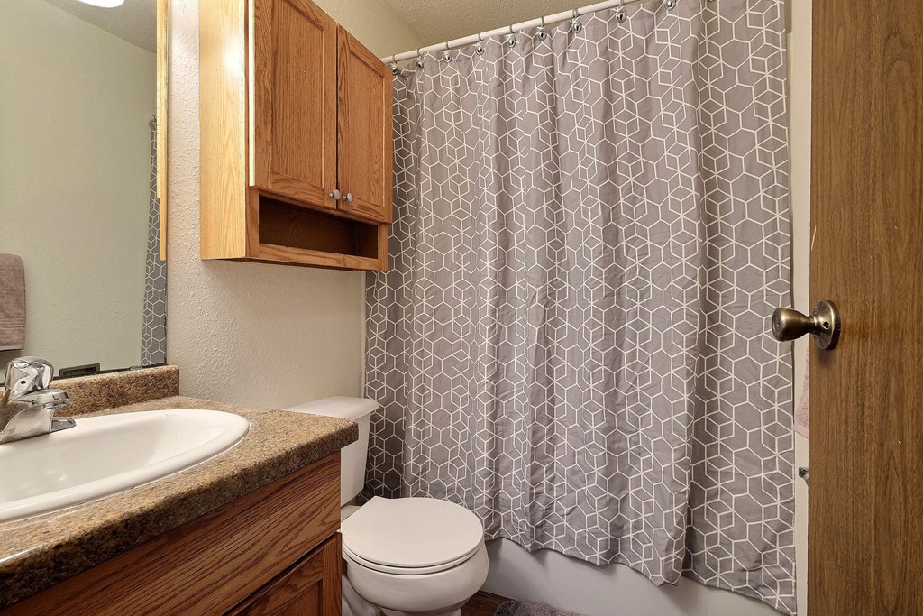 a bathroom with a shower and a toilet and a sink. Fargo, Pacific Park II Apartments