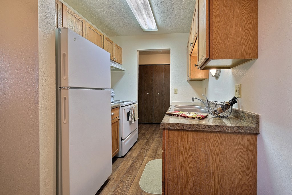 a kitchen with white appliances and wood cabinets. Fargo, Pacific Park II Apartments