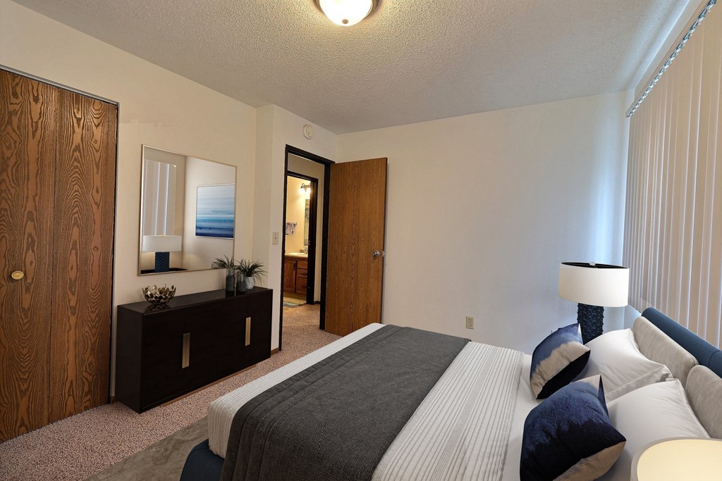 a bedroom with a bed and a dresser and a mirror. Fargo, ND Pacific South Apartments