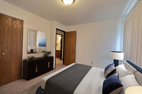 a bedroom with a bed and a dresser and a mirror. Fargo, ND Pacific South Apartments