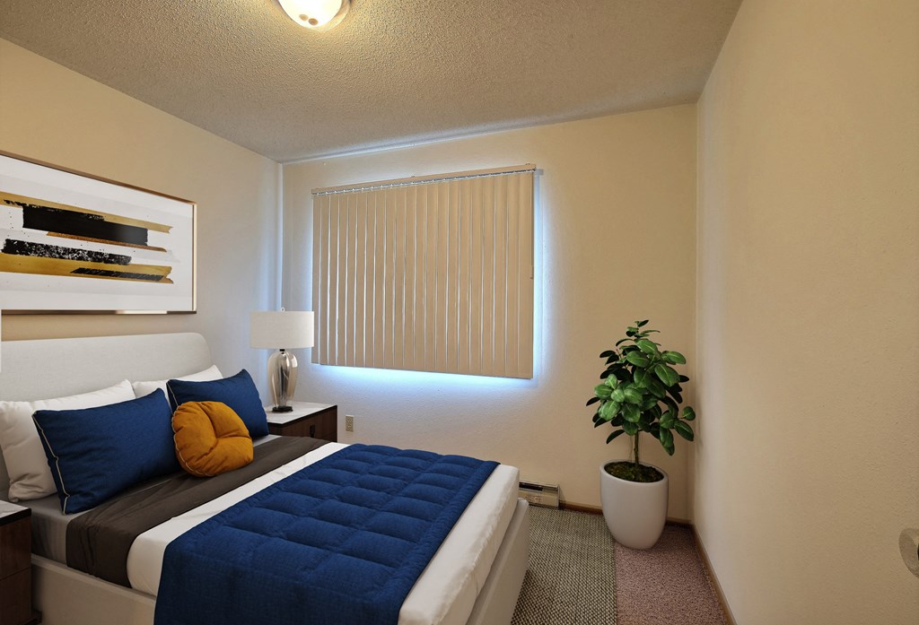 a bedroom with a large bed and a potted plant. Fargo, ND Pacific South Apartments