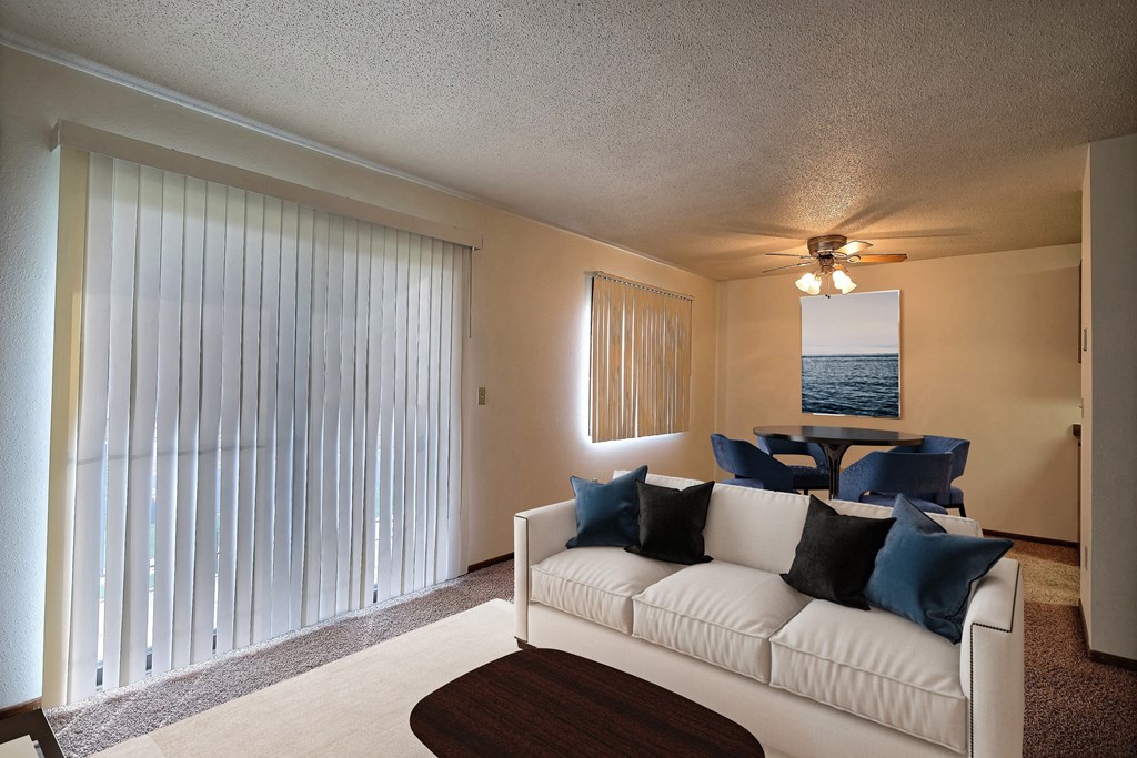 a living room with a white couch and a large window. Fargo, ND Pacific South Apartments