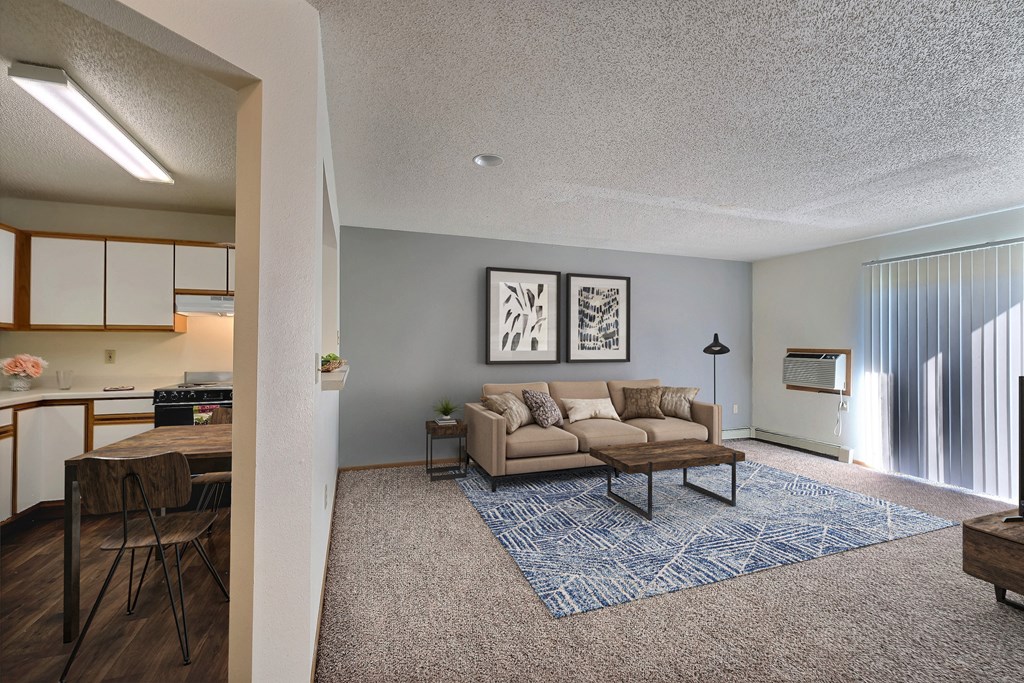 an open living room and kitchen with a couch and a table. Fargo, ND Park Place Apartments