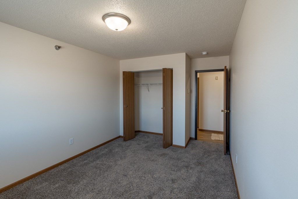 Fargo, ND Parkside Apartments. A bedroom with a carpeted floor and a door to a closet