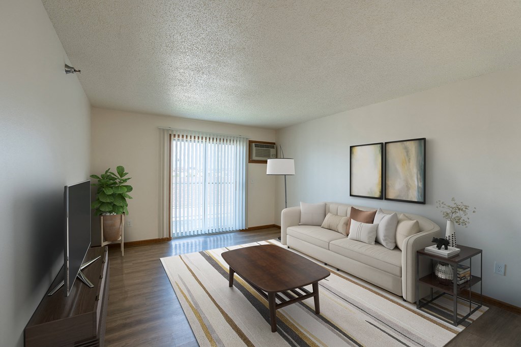 Fargo, ND Parkside Apartments. A living room with a couch, coffee table, tv, and a glass sliding door.