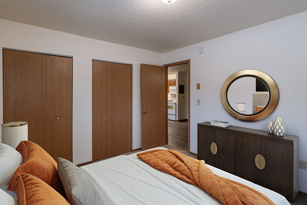 a bedroom with a bed and a dresser and a mirror. Fargo, ND Parkwood East and West Apartments