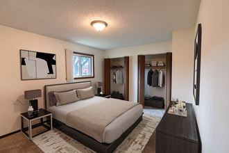 a bedroom with a bed and a dresser and a closet. Fargo, ND Patricia Ann Apartments
