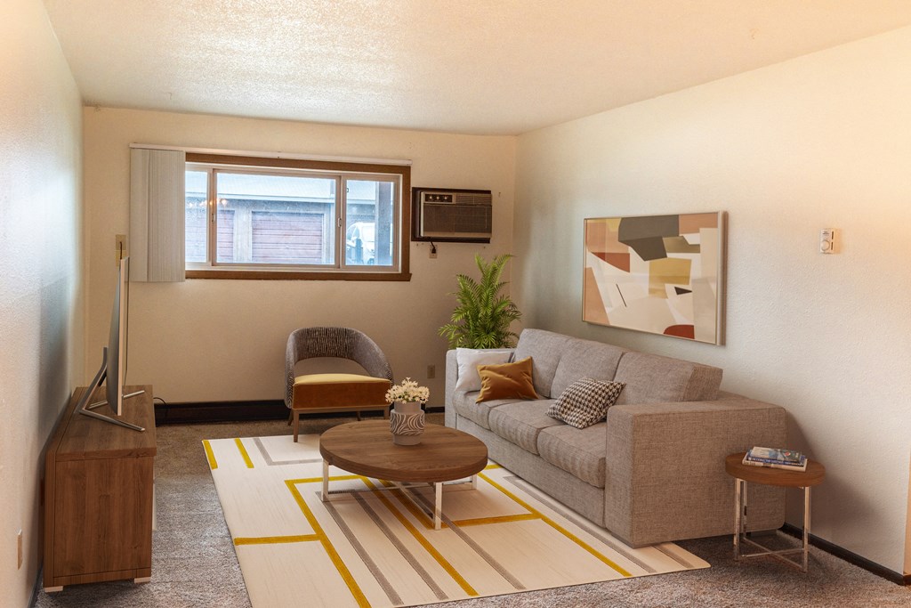 the living room of a small apartment with a couch and a chair. Fargo, ND Patricia Ann Apartments
