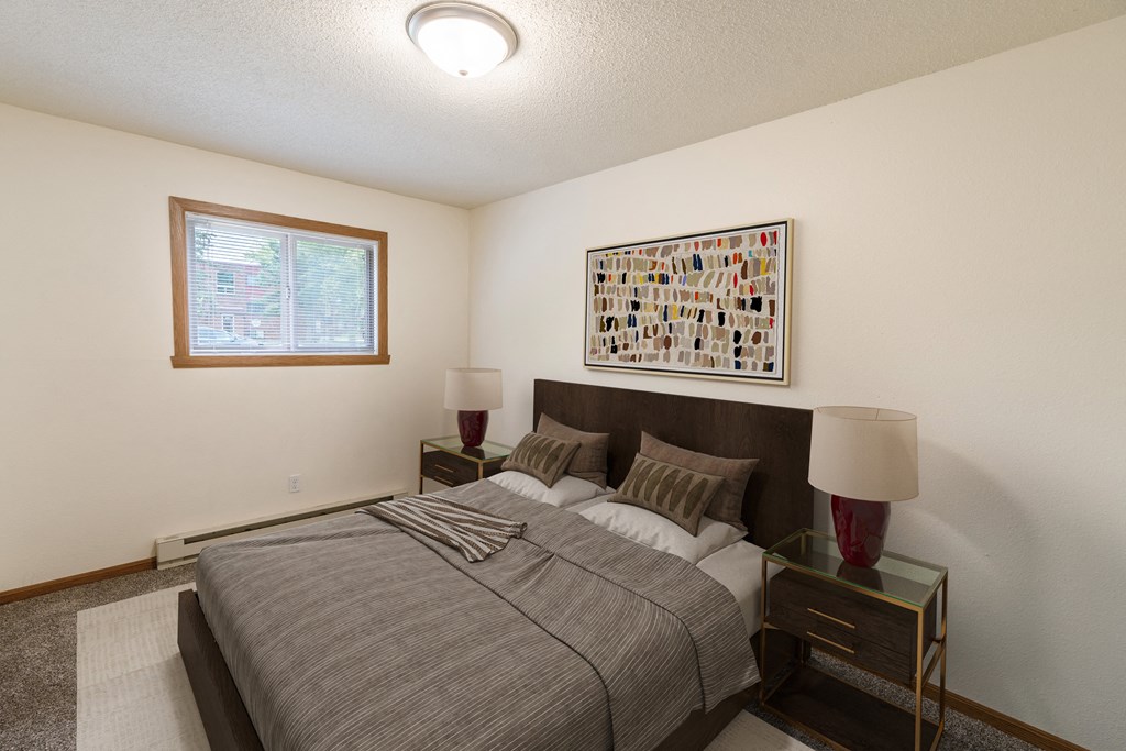 a bedroom with a bed and a window. Fargo, ND Patricia Ann Apartments
