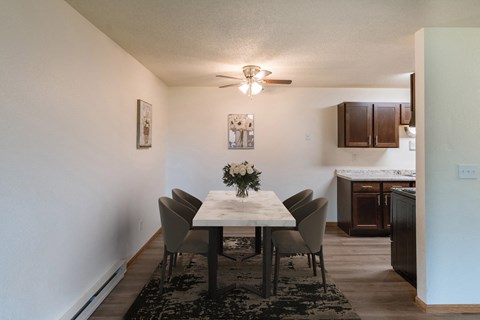 a dining room with a table and chairs and a kitchen with a ceiling fan