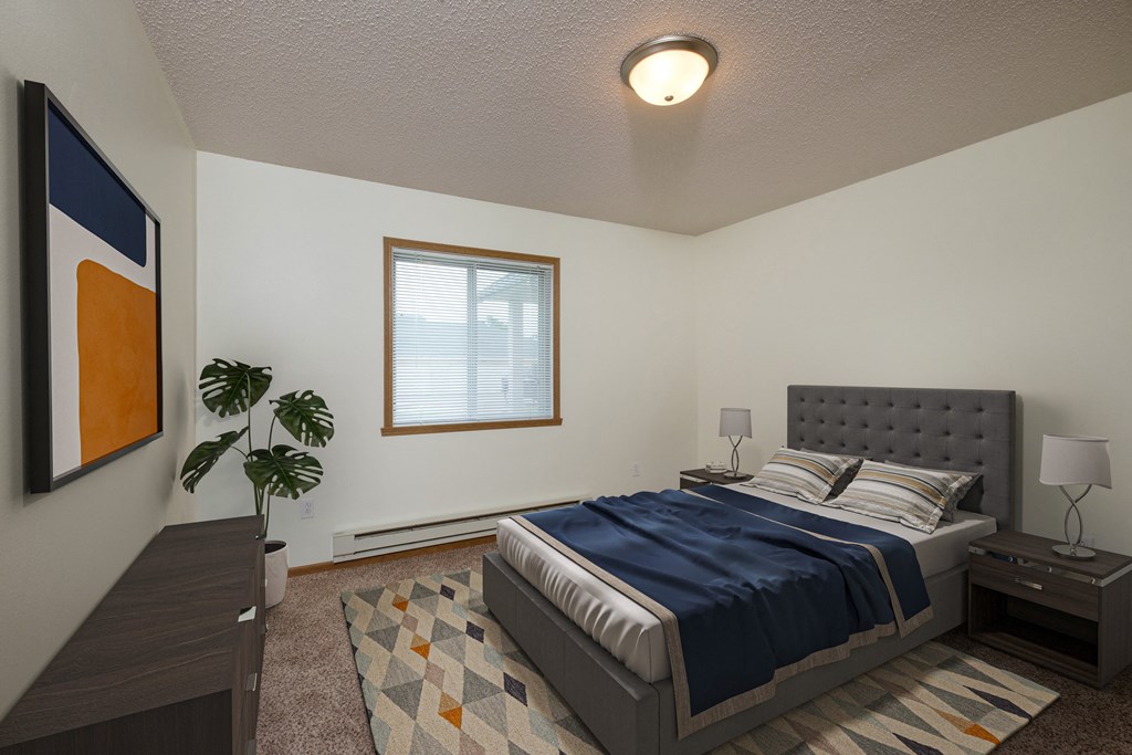 A bedroom with a bed and a dresser and a window. Fargo, ND Pinehurst Apartments.