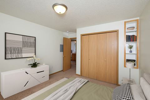 A bedroom with a bed and a dresser and a closet. Fargo, ND Pinehurst Apartments