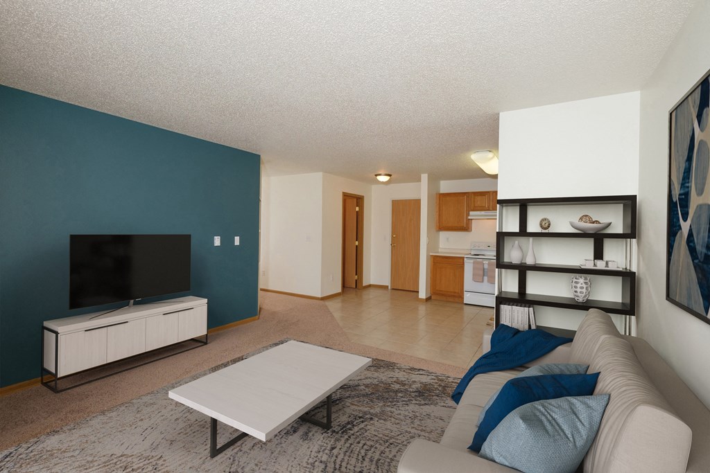 A living room with a couch and a coffee table and a televisio. Fargo, ND Pinehurst Apartments.
