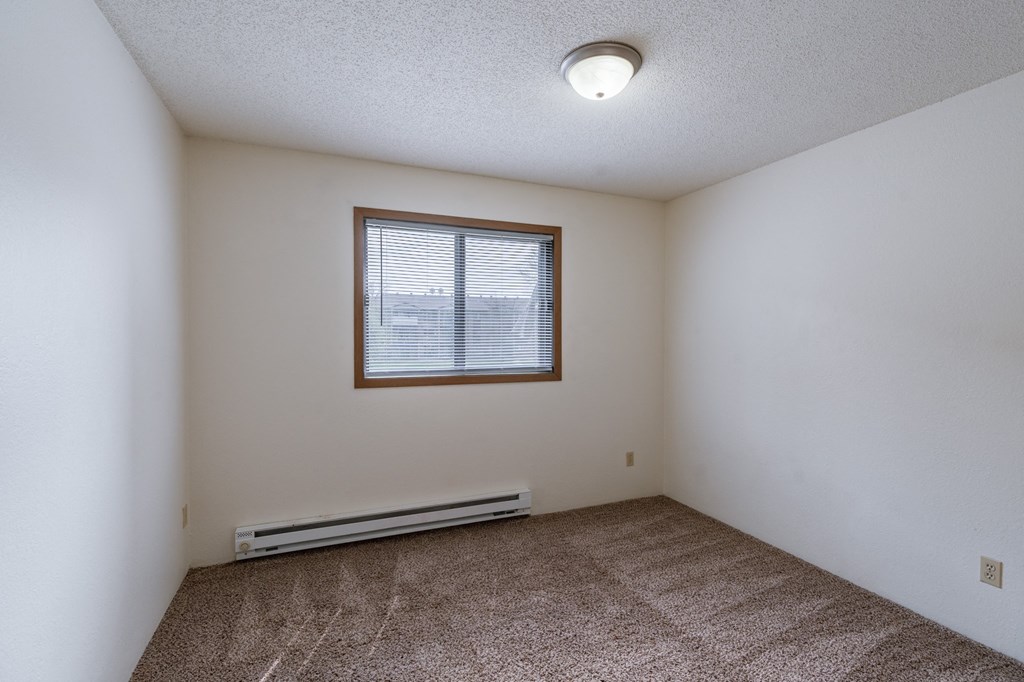 bedroom of an empty apartment with carpet and a window. Fargo, ND Place One Apartments