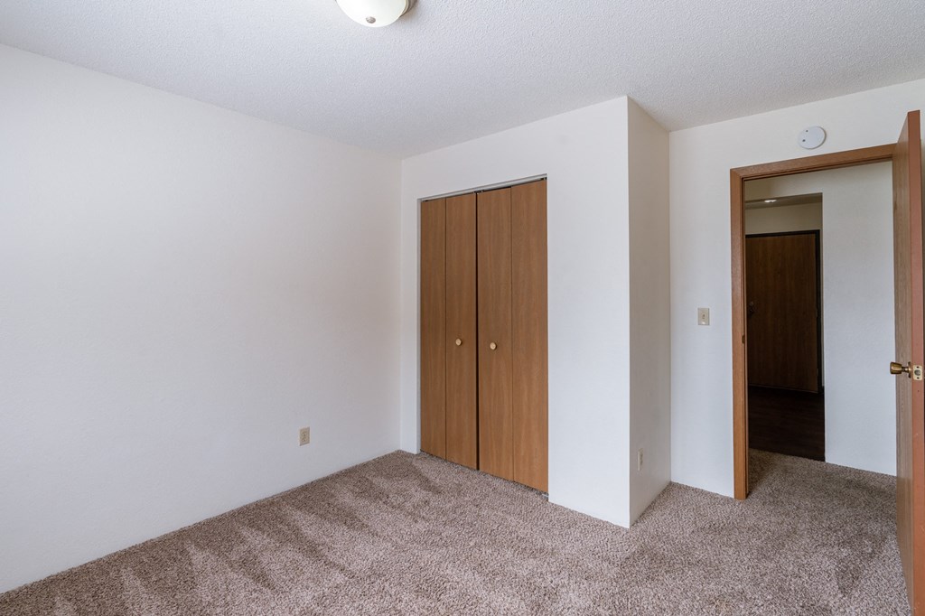 a bedroom with carpet and a door to a closet. Fargo, ND Place One Apartments