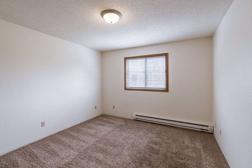 a bedroom with carpet and a window. Fargo, ND Place One Apartments