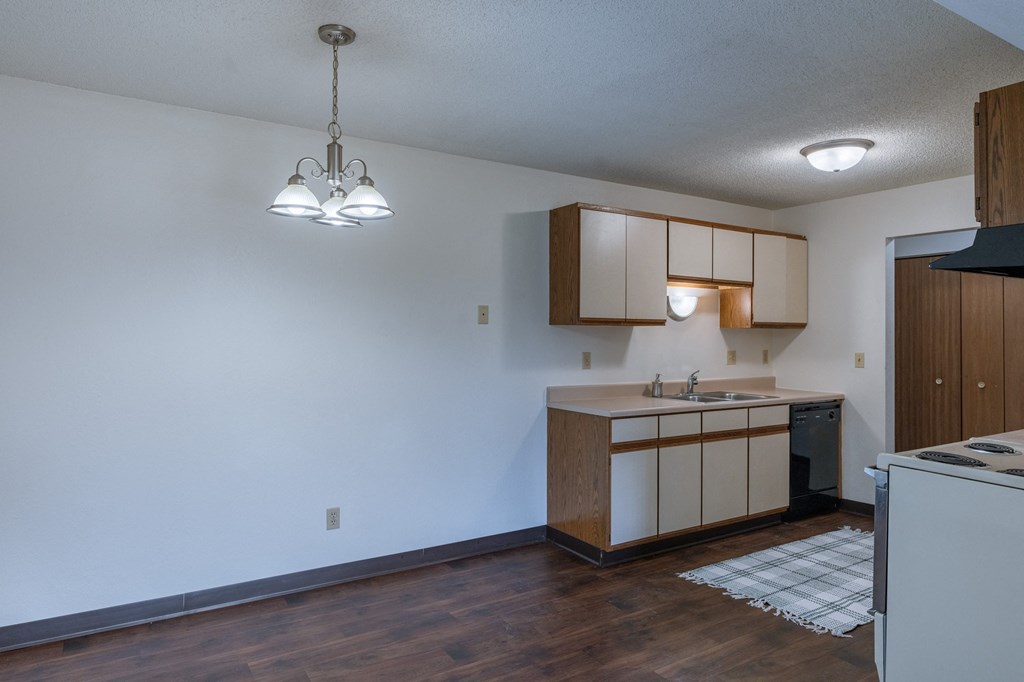 an empty kitchen with wood floors and white walls. Fargo, ND Place One Apartments