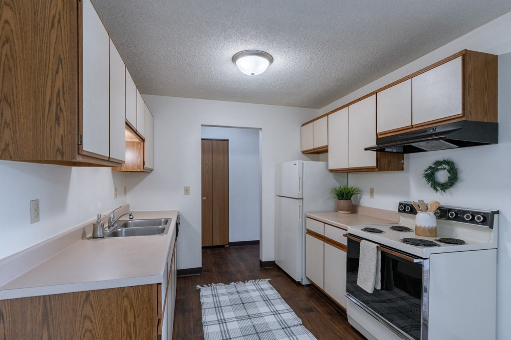 an empty kitchen with white appliances and wooden cabinets. Fargo, ND Place One Apartments