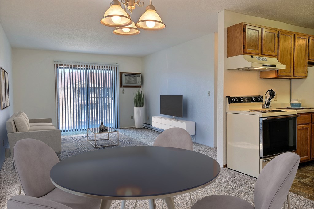 A living room with a table and chairs and a kitchen with a television. Fargo, ND Place One Apartments.