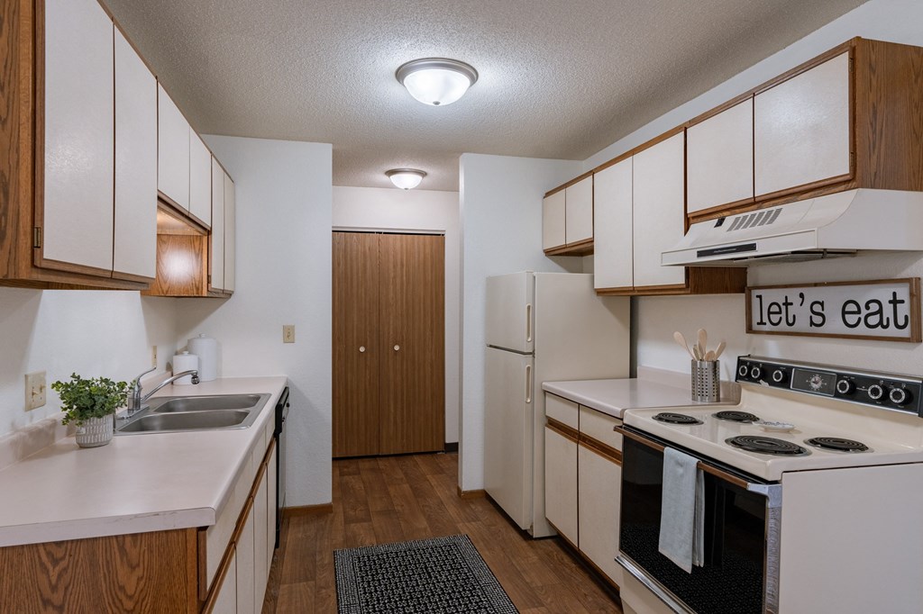 a kitchen with white appliances and wooden cabinets. Fargo, ND Place One Apartments
