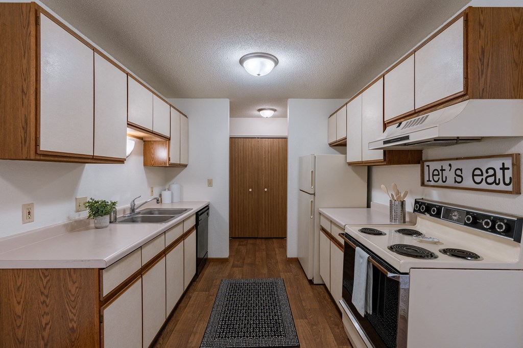 a kitchen with white appliances and wooden cabinets. Fargo, ND Place One Apartments