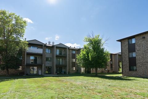 An exterior view of a brick apartment building with green grass. Fargo, ND Place One Apartments.