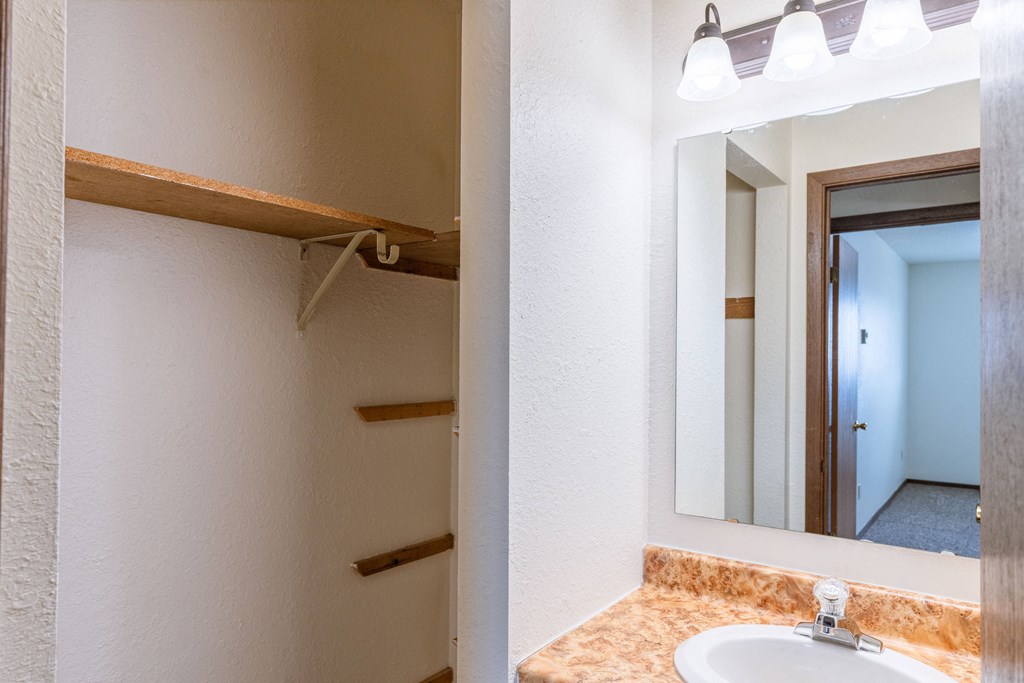 the bathroom has a large mirror and a sink. Fargo, ND Plumtree Apartments