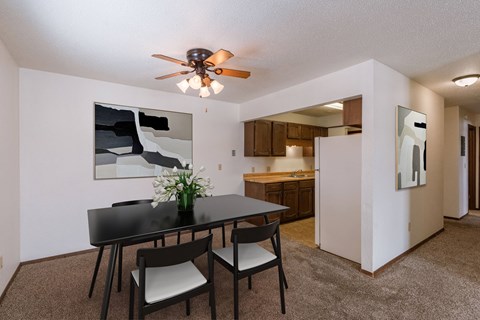 a dining area with a table and chairs and a ceiling fan. Fargo, ND Plumtree Apartments