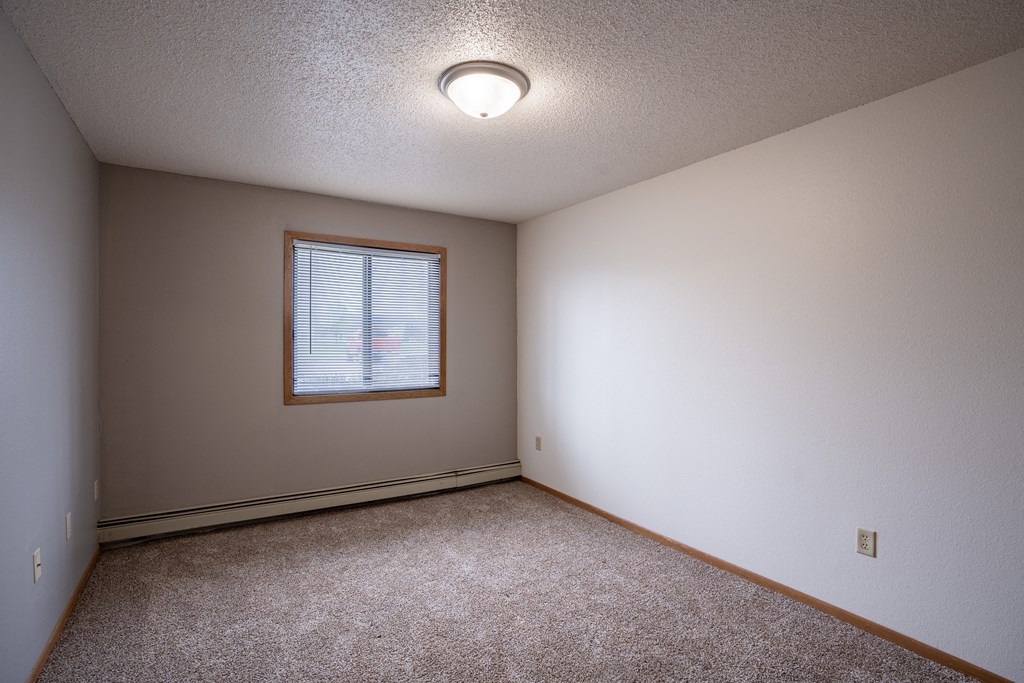 a bedroom with carpet and a window. Fargo, ND  Prairie Park Apartments