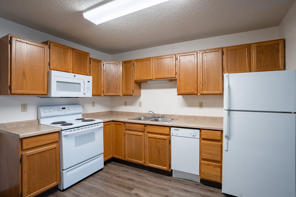 an empty kitchen with white appliances and wooden cabinets