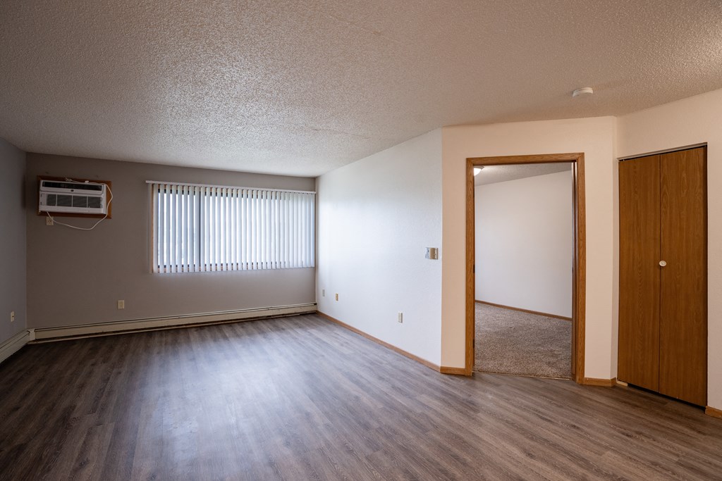 a living room with wood flooring and a door to a bedroom. Fargo, ND  Prairie Park Apartments