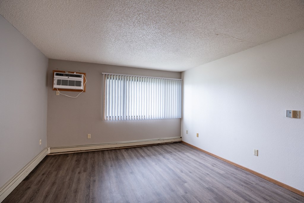 the living room of an empty apartment with wood flooring and a window