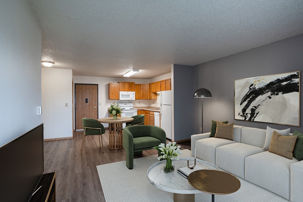 a living room and kitchen with a white couch and a table. Fargo, ND Prairie Park Apartments