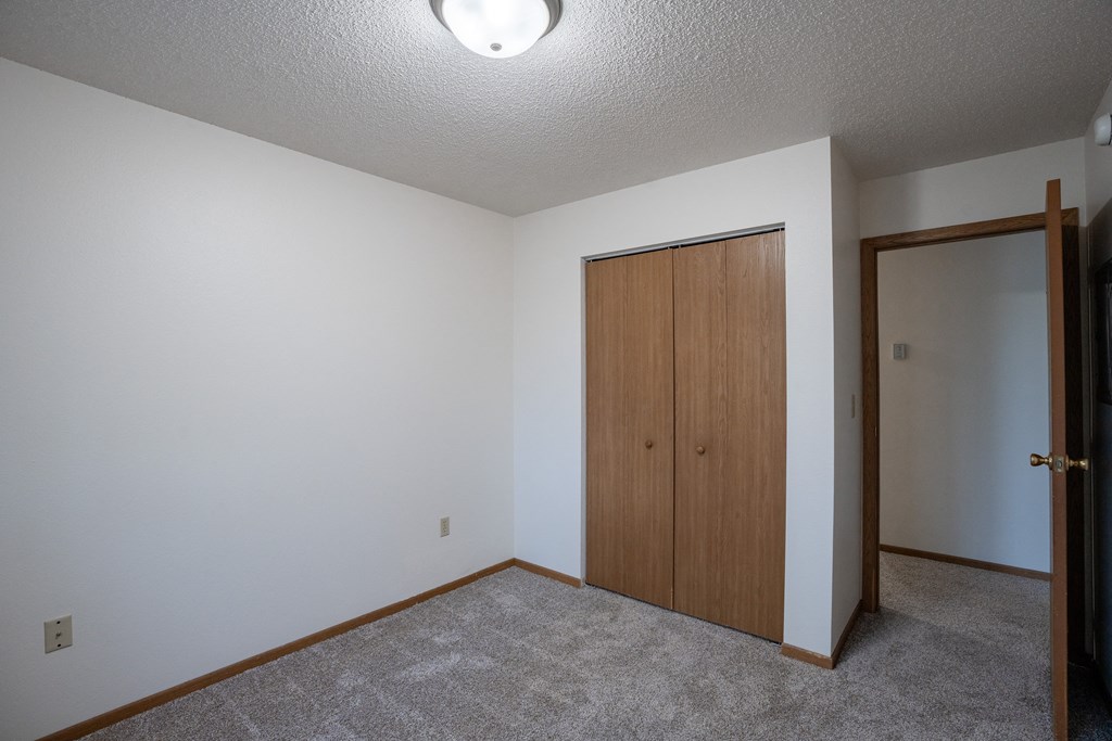a bedroom with a door to a closet and a carpeted floor. Fargo, ND  Prairie Park Apartments
