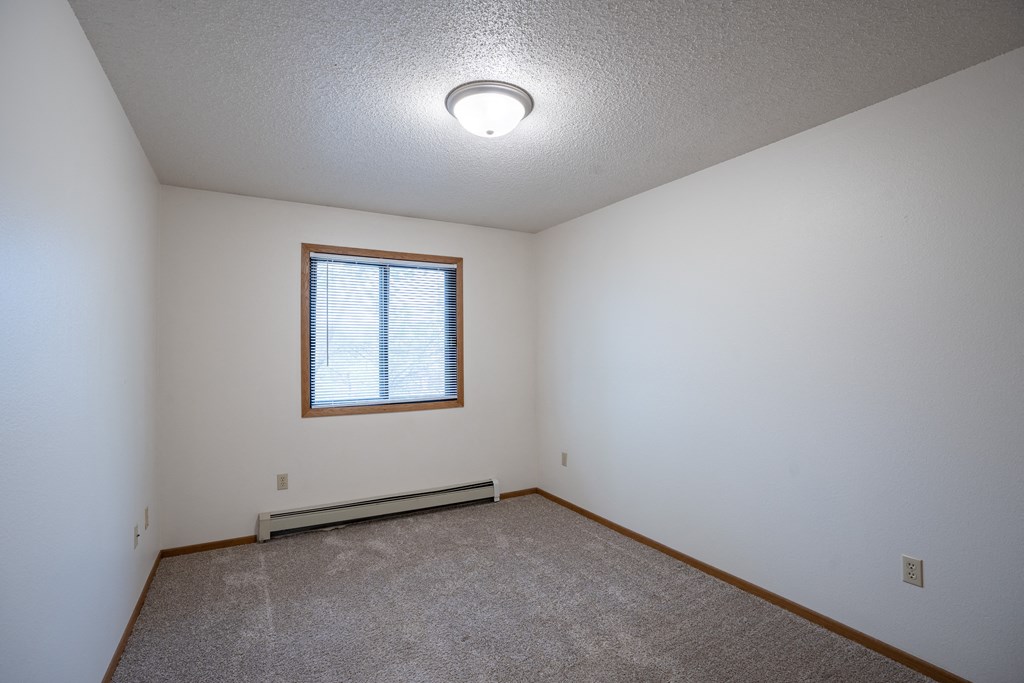 a bedroom with white walls and a window. Fargo, ND  Prairie Park Apartments