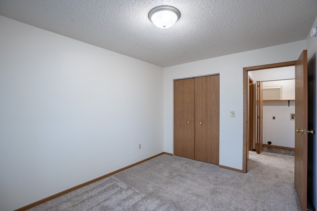 a bedroom with carpet and a door to a closet. Fargo, ND  Prairie Park Apartments