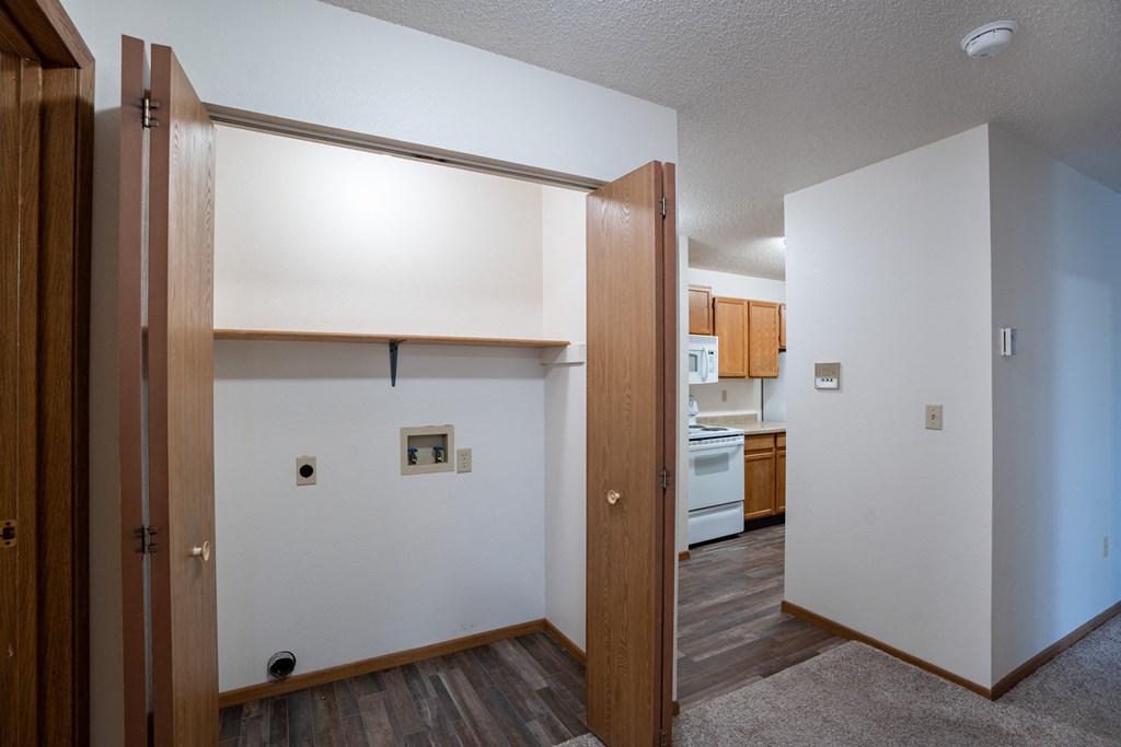 the view of a kitchen from a living room with wood floors and white walls. Fargo, ND  Prairie Park Apartments