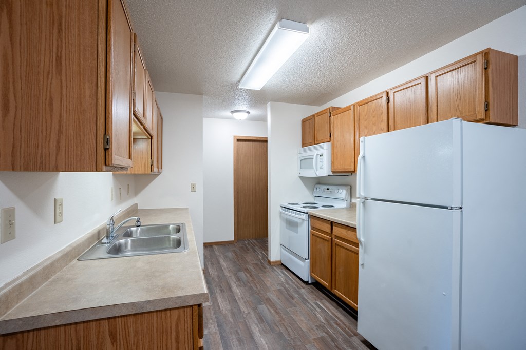 a kitchen with white appliances and wood cabinets. Fargo, ND  Prairie Park Apartments